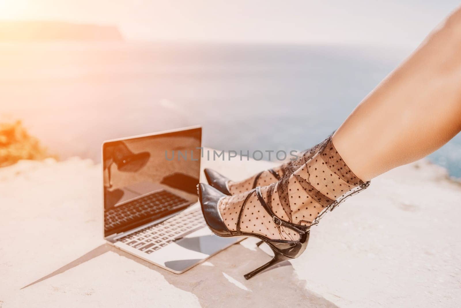 Woman sea laptop. Business woman in yellow hat freelancer with laptop working over blue sea beach. Girl relieves stress from work. Freelance, digital nomad, travel and holidays concept by panophotograph