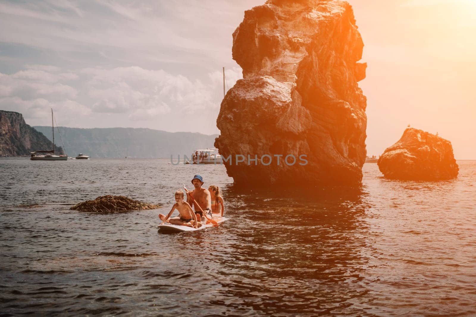 Family sea sup. Young happy father with his son and daughter Floating on a SUP board, paddling in blue sea water. summer vacation and Dad and Son Daughter concept. by panophotograph