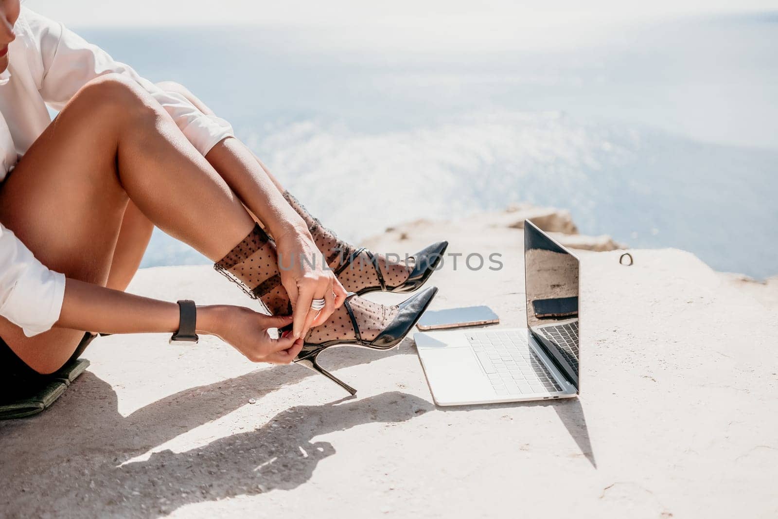 Happy girl doing yoga with laptop working at the beach. beautiful and calm business woman sitting with a laptop in a summer cafe in the lotus position meditating and relaxing. freelance girl remote work beach paradise