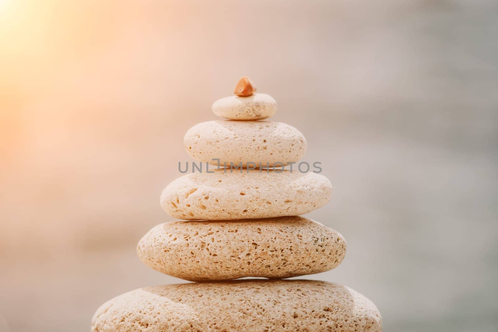 Calm pebble beach with pyramid stones and warm sunset on the sea background. Perfect travel destination for happy holidays, meditation, and relaxation at spa. concept of calmness and tranquility. by panophotograph