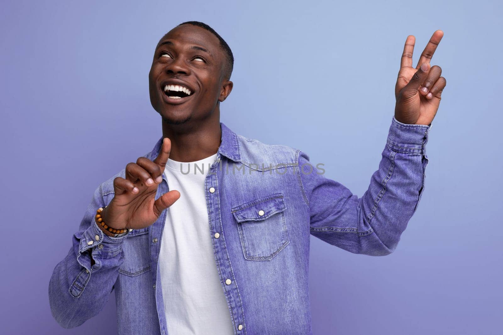 close-up portrait of a young handsome well-groomed african guy in a denim jacket on a studio background.