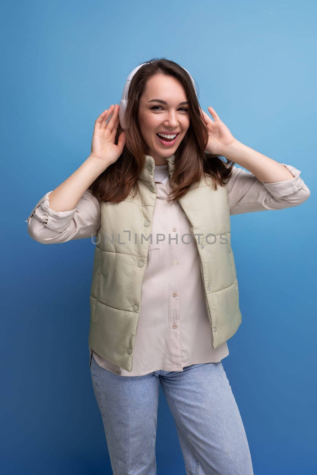 energetic young brunette woman relaxing to music using headphones and mobile phone.