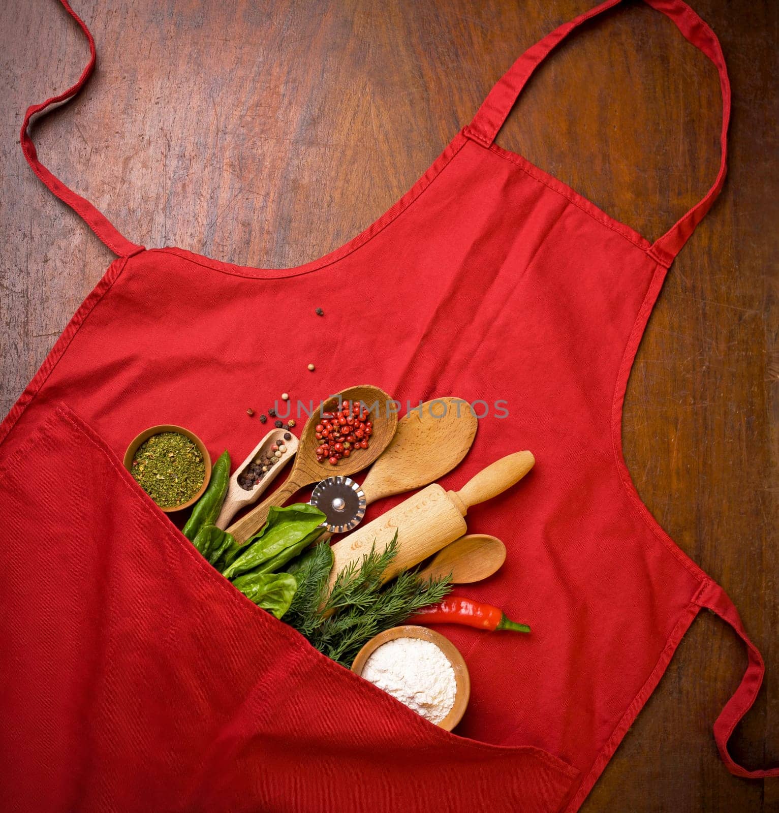 Baking background with red apron, rolling pin, herbs and kitchen utensils on a black background. View from above. Flat style. High quality photo by aprilphoto