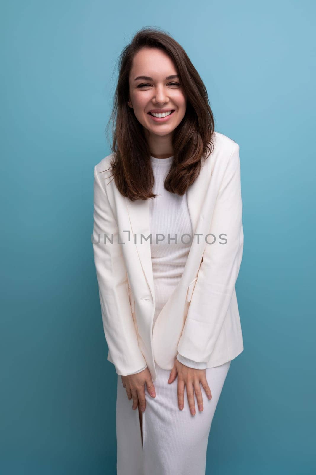 pleasant european brunette young woman in a white dress with cheerful emotions on her face.