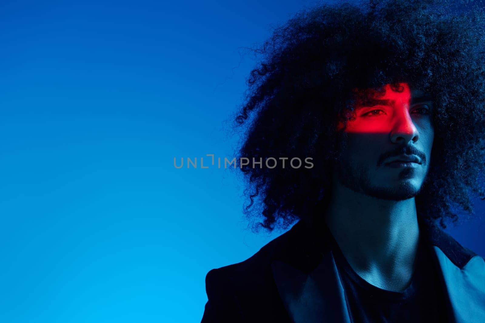 Fashion portrait of a man with curly hair on a blue background, multinational, colored light, trendy, modern concept. High quality photo