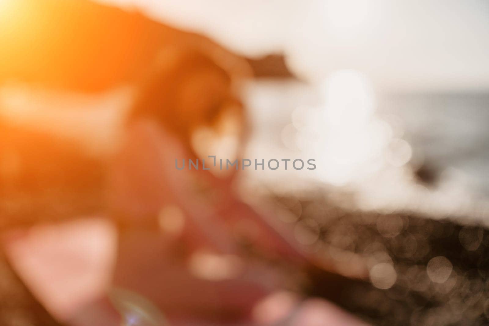 Young woman with black hair, fitness instructor in pink sports leggings and tops, doing pilates on yoga mat with magic pilates ring by the sea on the beach. Female fitness daily yoga concept