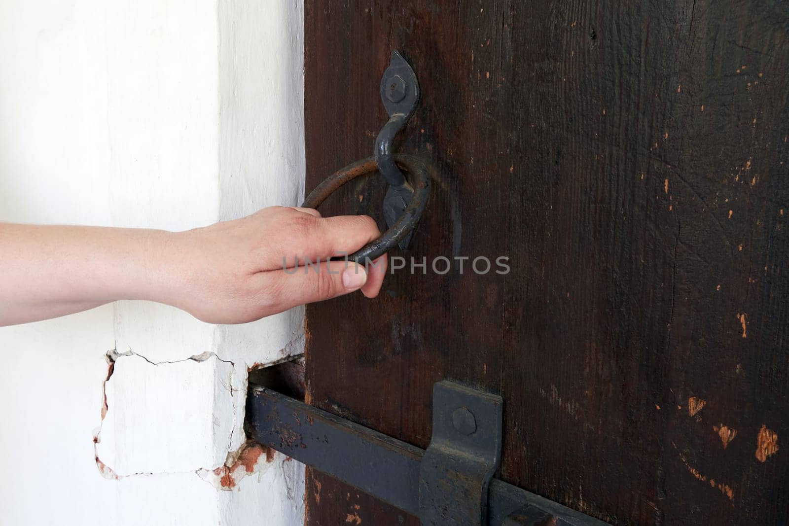 Woman's hand trying to open an antique wooden door close up