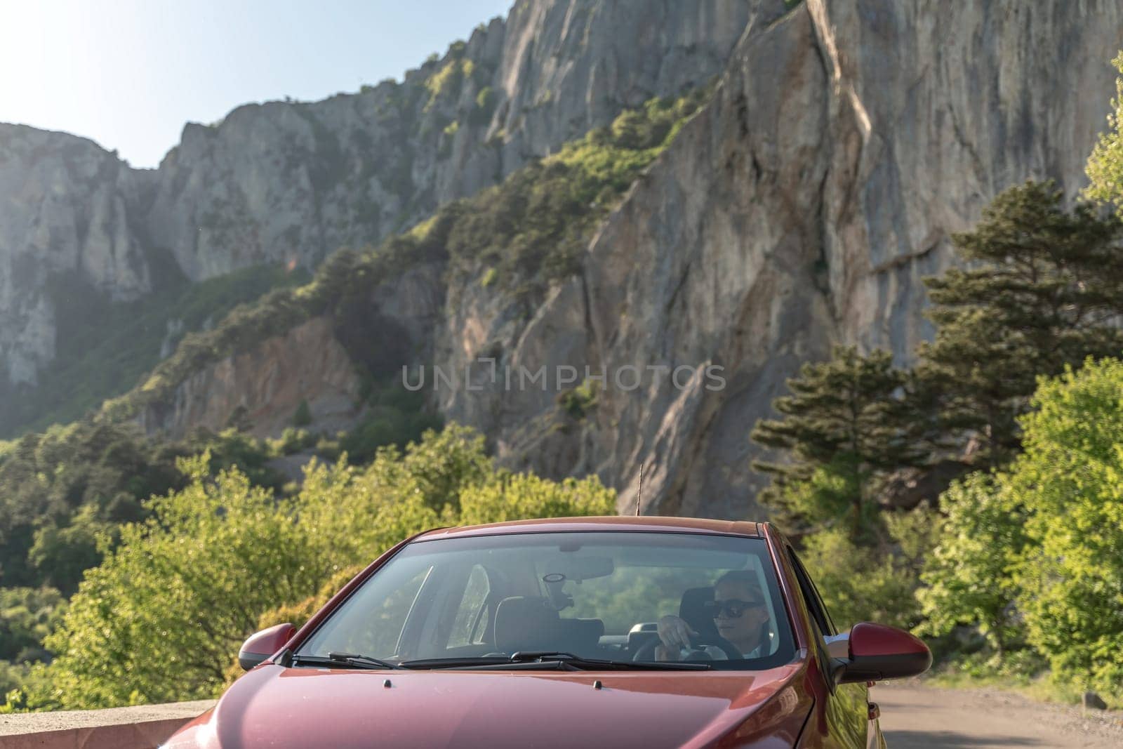 Woman driving a car. A lady in sunglasses takes the wheel of her new car. Rides along the road against the backdrop of mountains and the sea