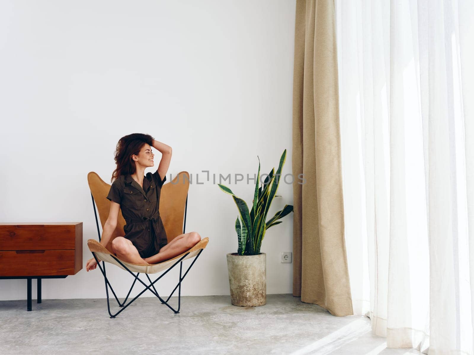 Woman sitting in a leather armchair near the window smiling , modern stylish interior Scandinavian lifestyle, copy space. High quality photo