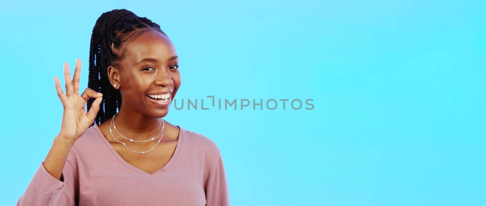 Perfect, sign and woman with okay hand gesture smile and happy with mockup space isolated in a studio blue background. Portrait, satisfaction and African American woman with support and winning emoji.