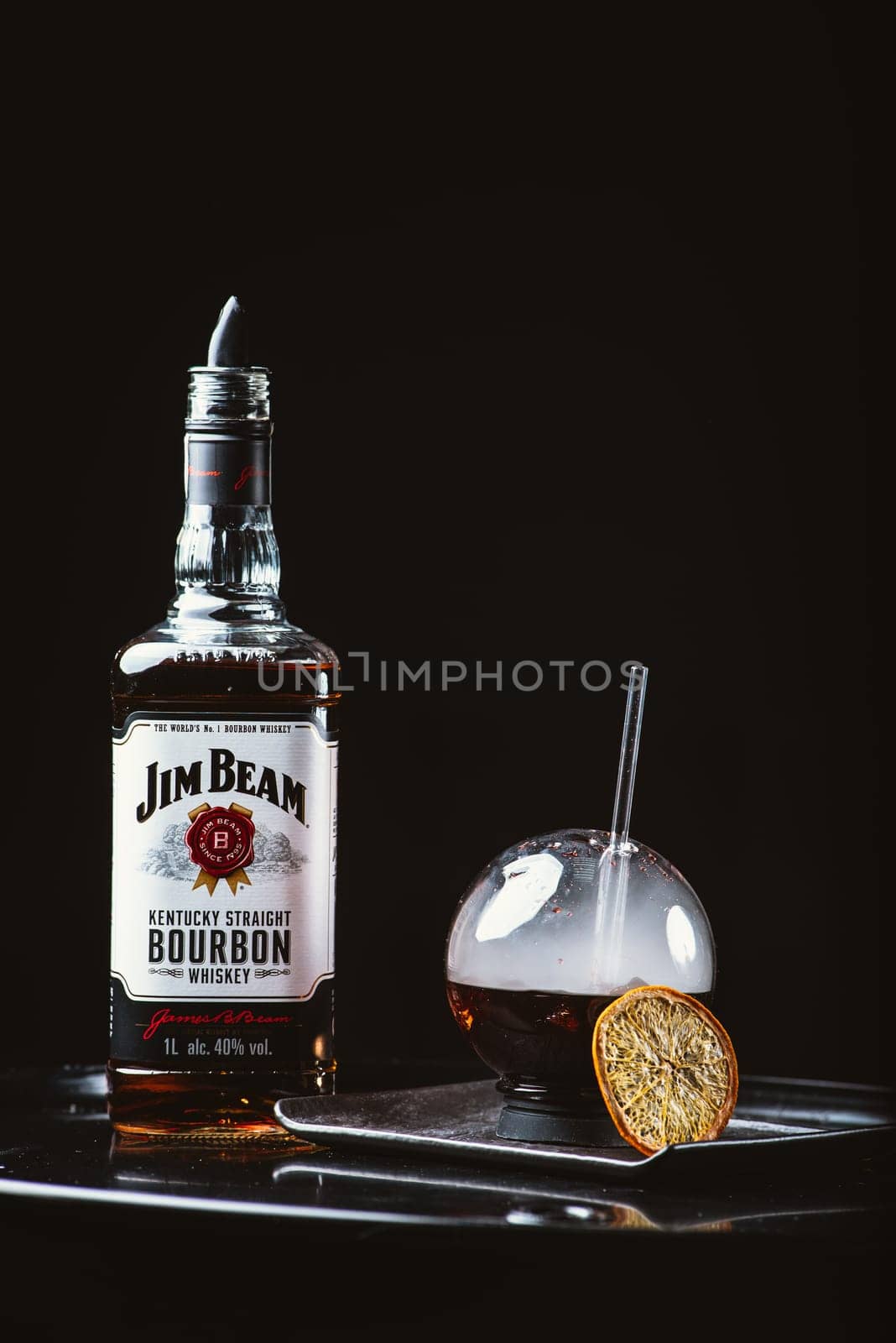 Odessa, Ukraine - February 07, 2020: Jim Beam is one of best selling brands of bourbon. Alcohol with smoke. Jim Beam bottle arranged with a spherical glasses on black background. by Renisons