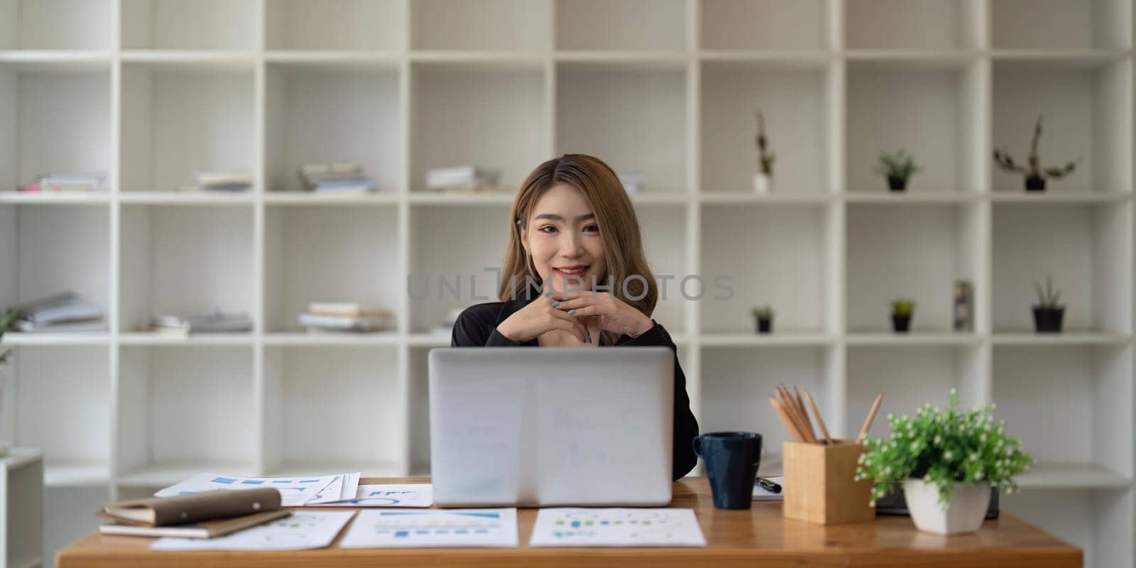 Happy young Asian business woman working at modern with a laptop.