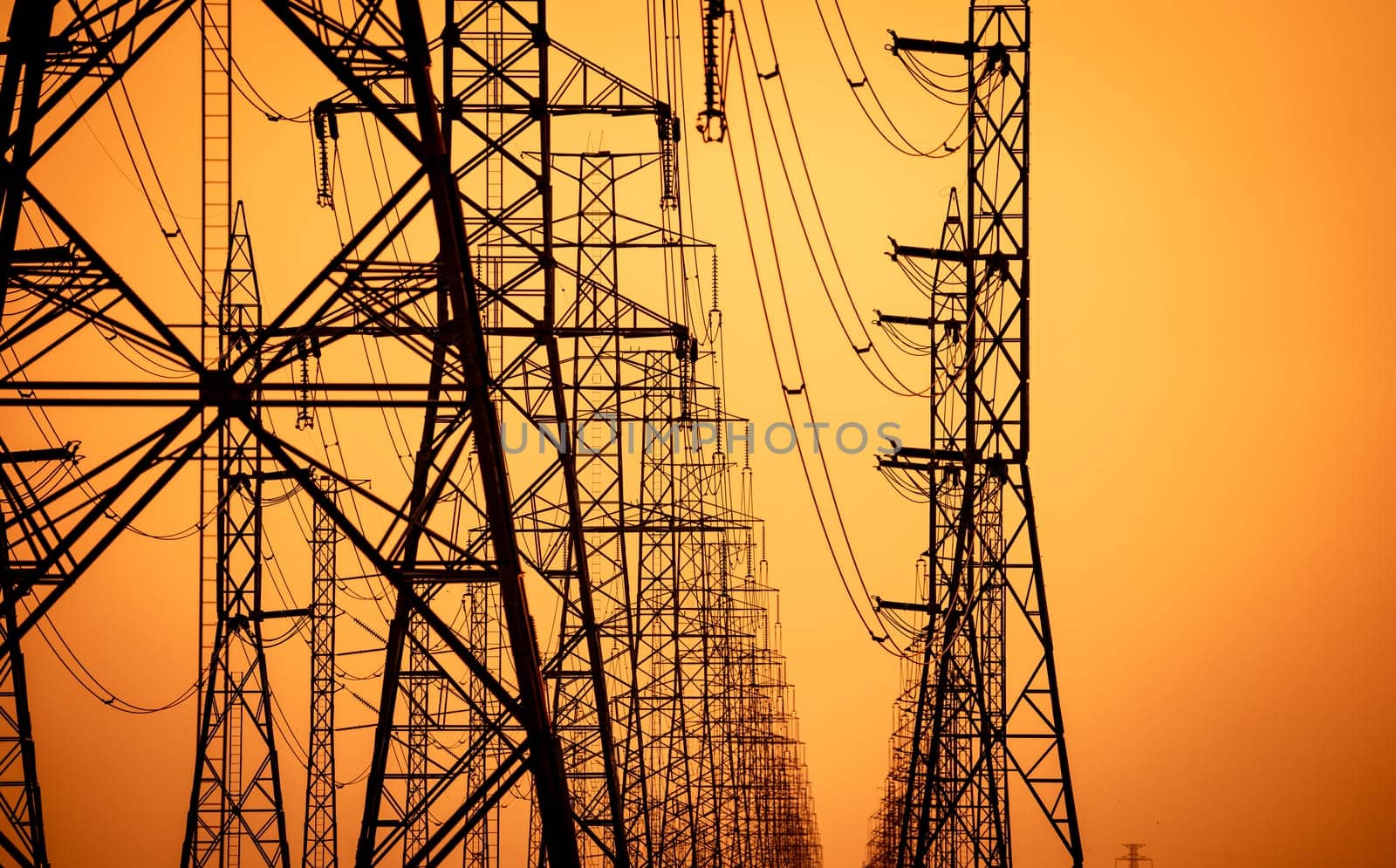 High voltage electric transmission tower. High voltage power lines on electric pylon against a sunset sky. Electrical infrastructure. Energy crisis. Electric power distribution. Energy distribution.