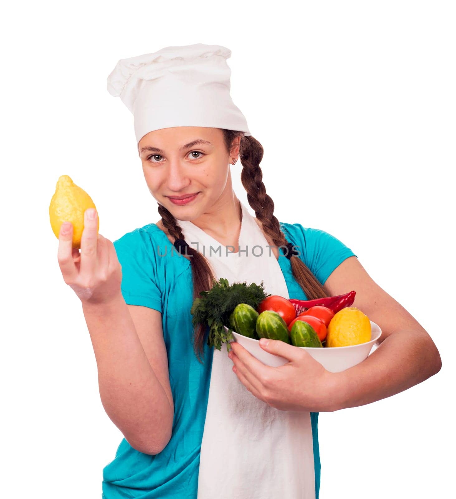 Girl teenager in a cap of cook with vegetables, lemon,