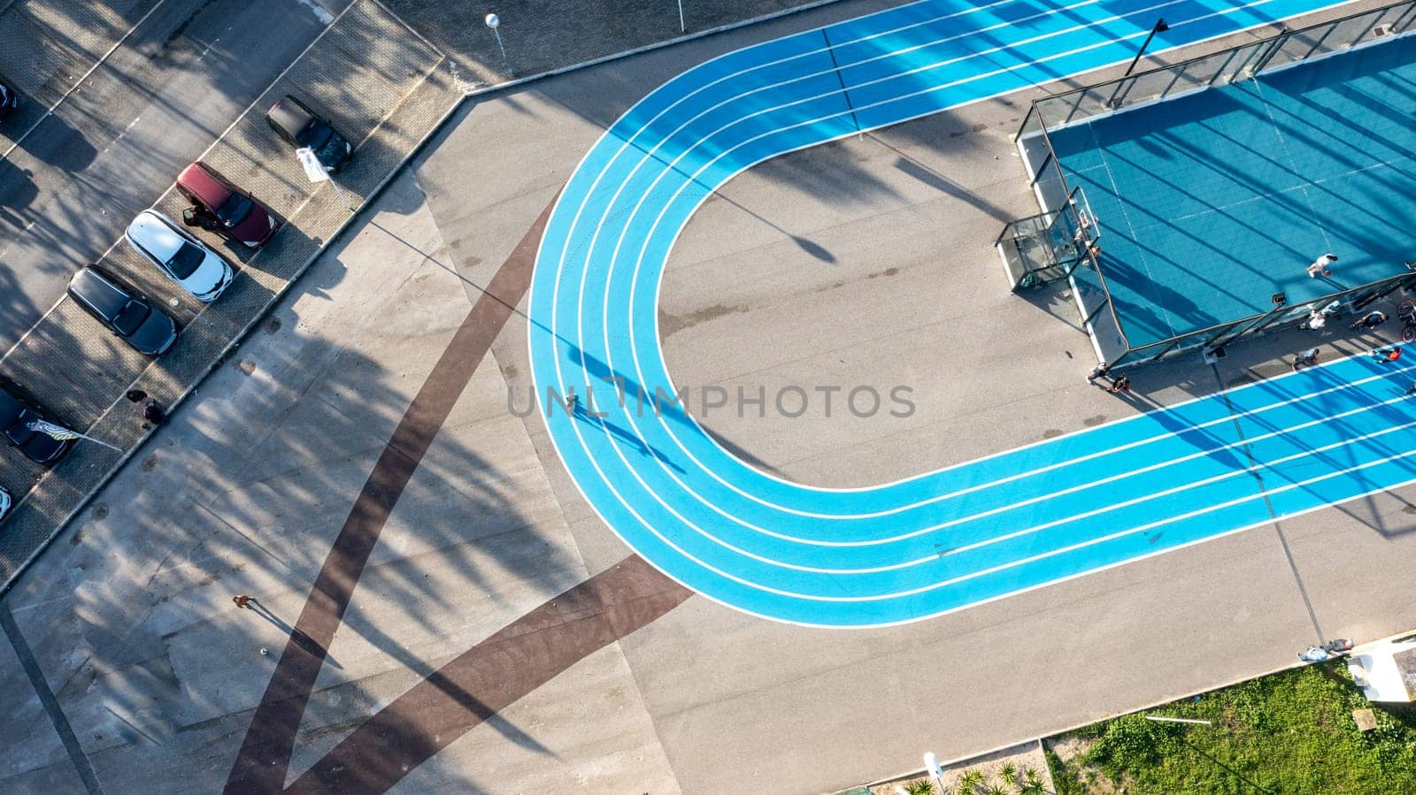 Blue running track on public sports ground next to a football and basketball court, view from above, drone photography, aerial view