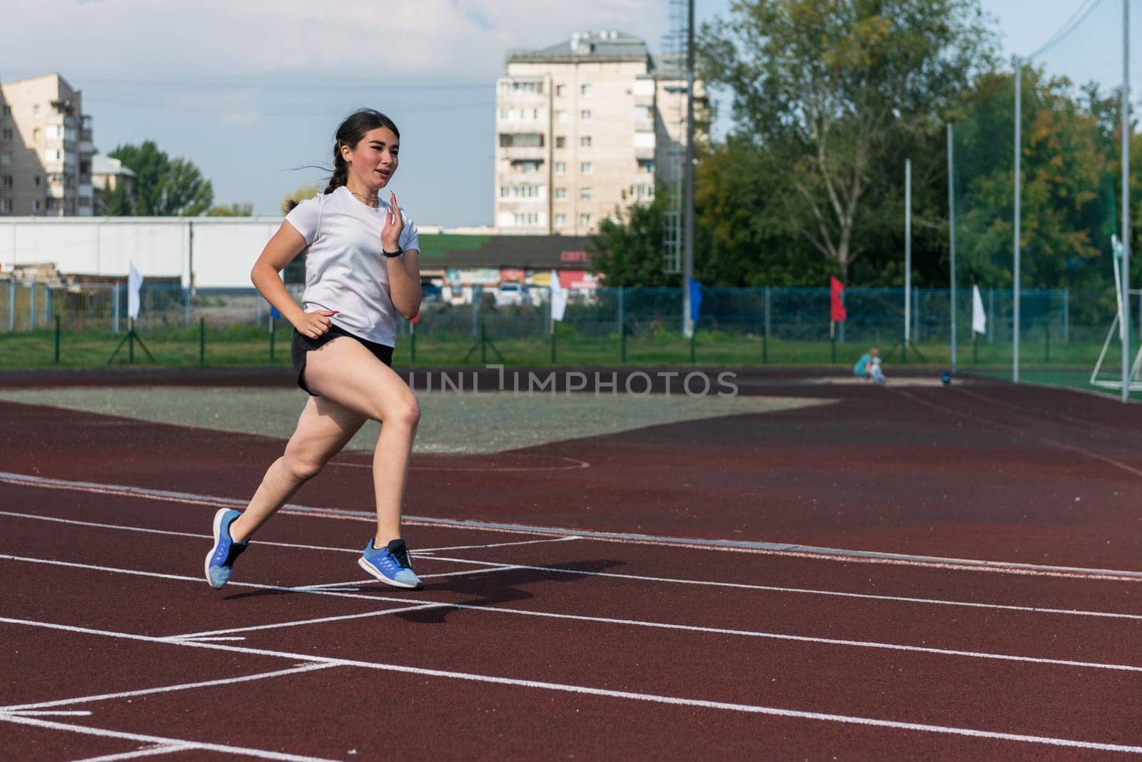 Young girl running on the running track at the stadium outdoors