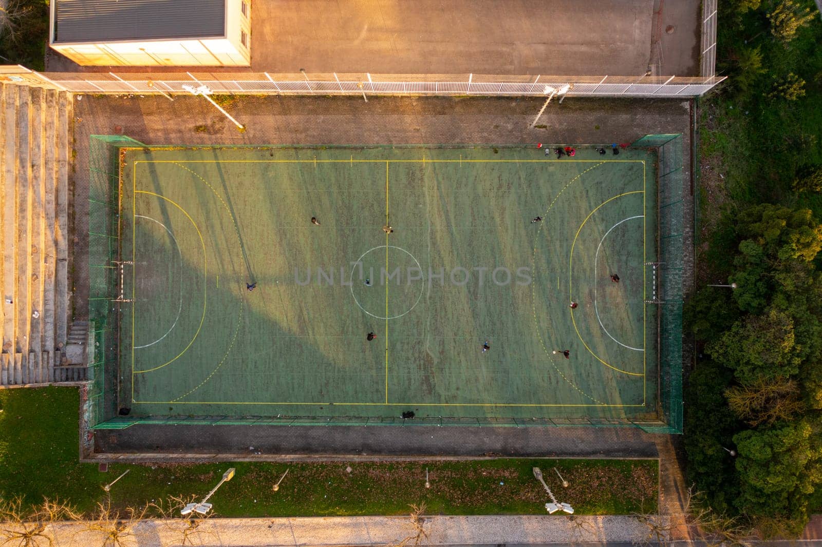 Aerial view of sport court in public park. Used to practice football. Top view. Sunny day. Sunset. Drone photo.