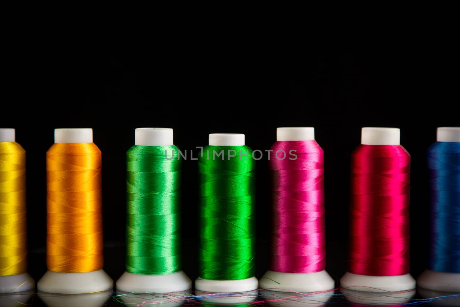 set of different color sewing threads,on black background. by Rawlik
