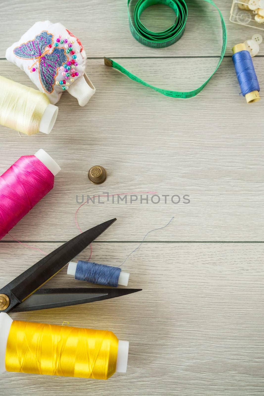 a set of tools and threads for sewing clothes, on a wooden background.