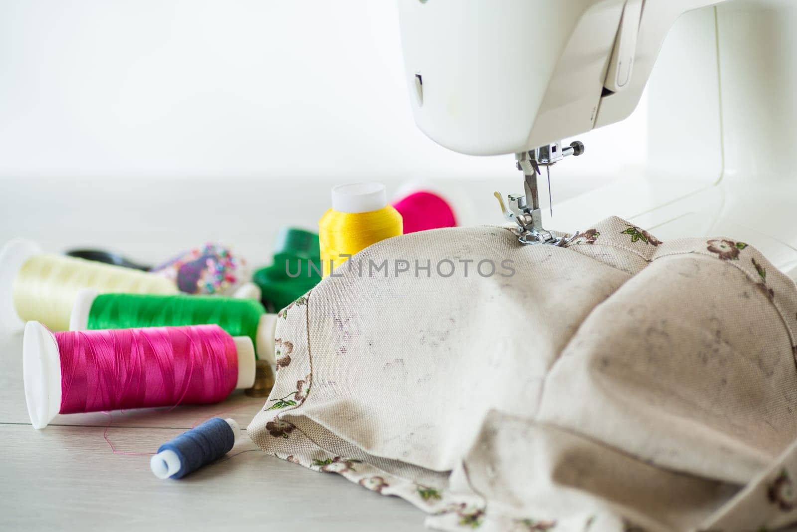Sewing machine with fabric and threads for sewing, close-up. The working process by Rawlik