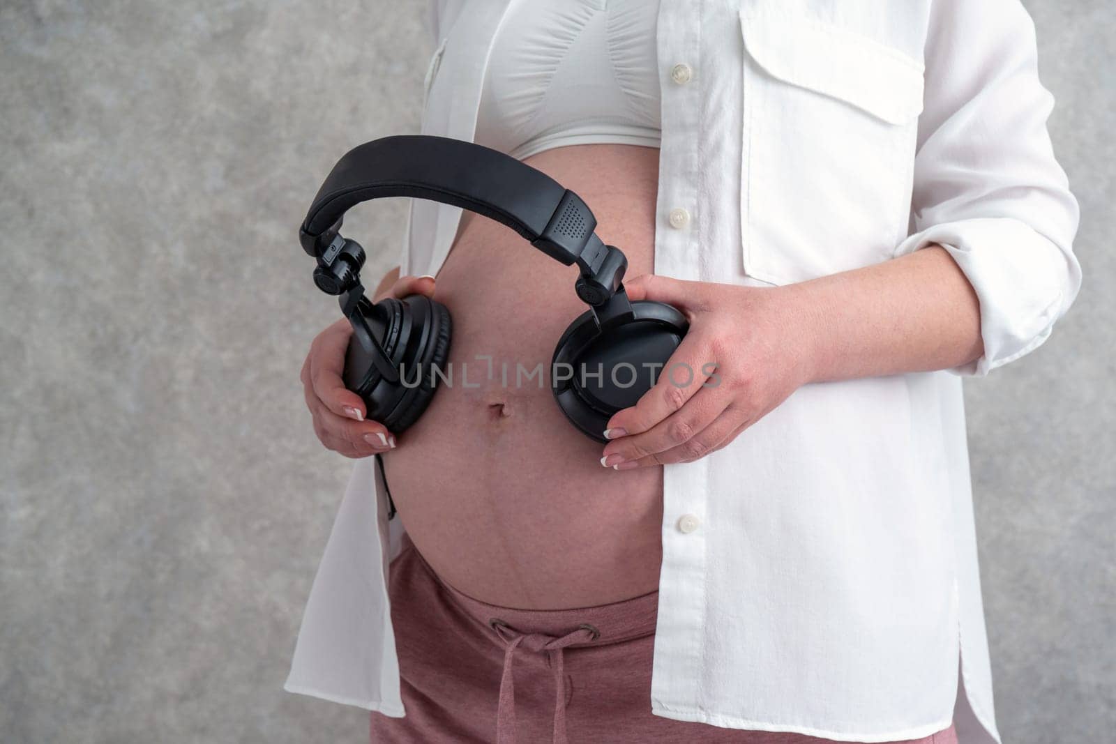 Pregnant woman playing music to her baby through headphones putting them on her belly by Mariakray