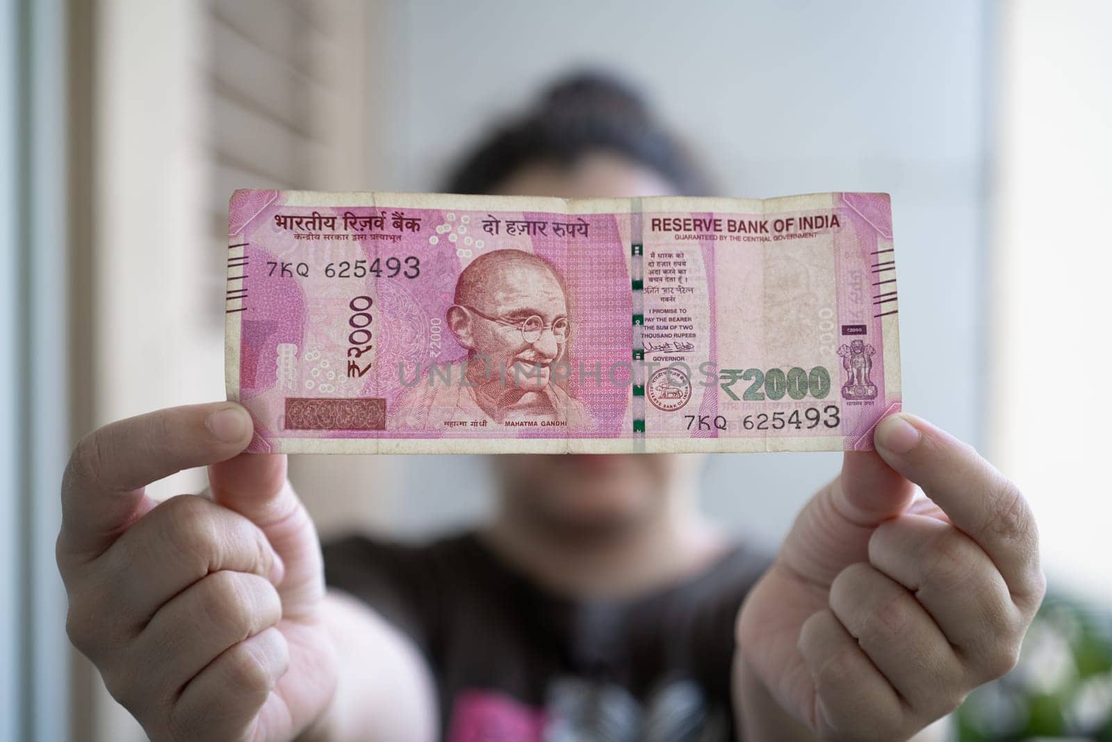 Woman holding out a Rs 2000 Indian bank note that has been removed from circulation through demonitization to reduce black money In India