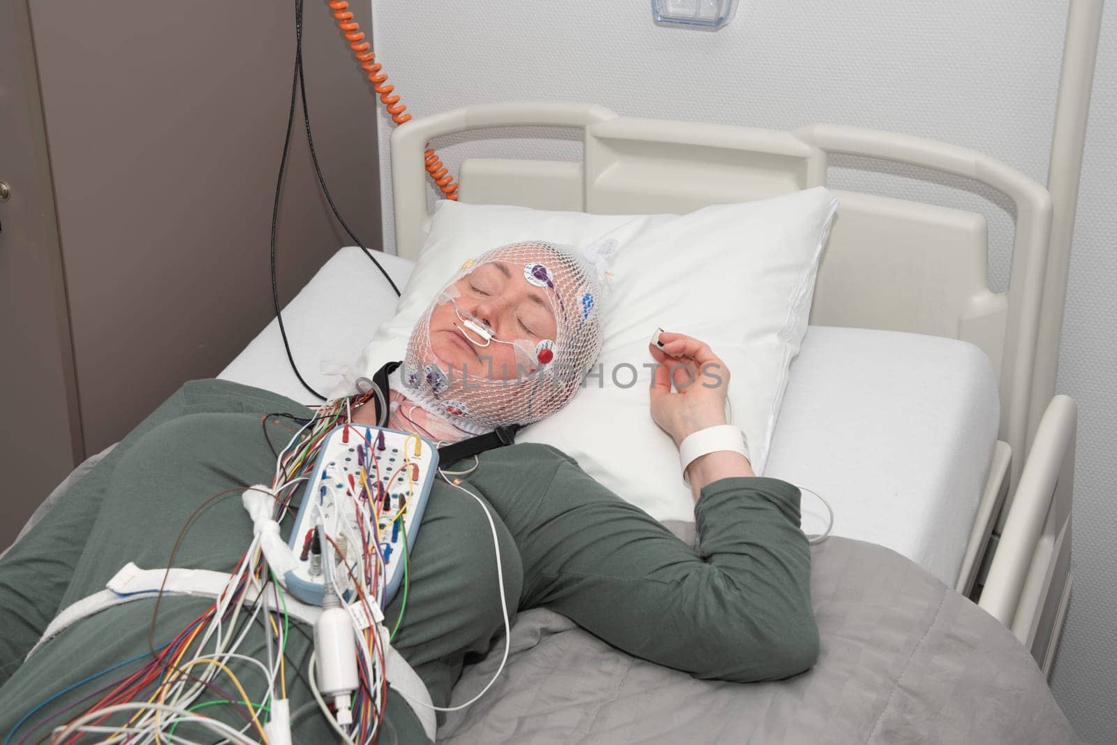 Middle aged woman measuring brain waves, examining polysomnography in sleep laboratory, High quality photo