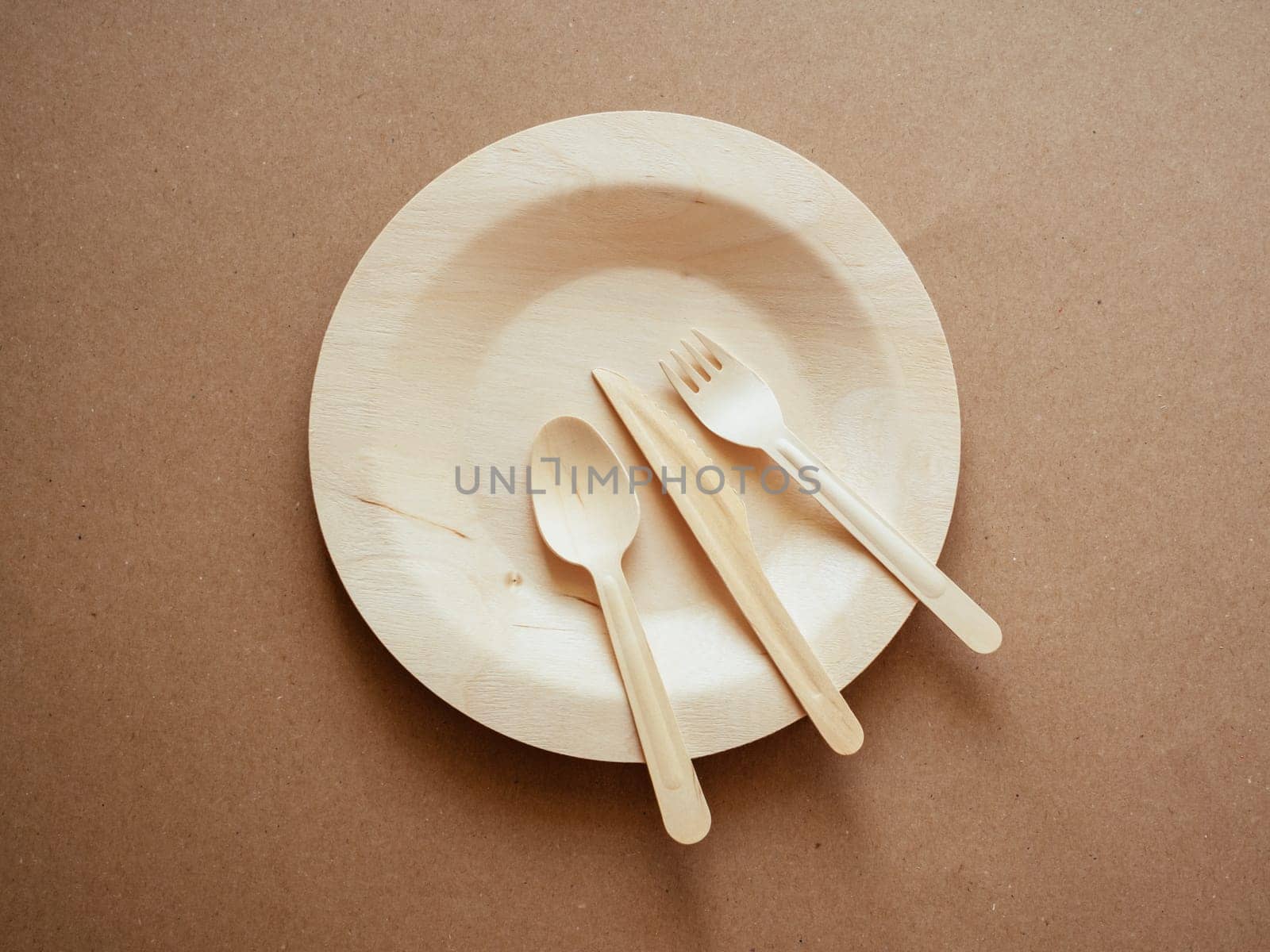 Ecology, zero waste. Top view of wooden, biodegradable, eco friendly tableware set on the plate on craft paper background. Concept of environment preservation and protection. Cope space, flat lay