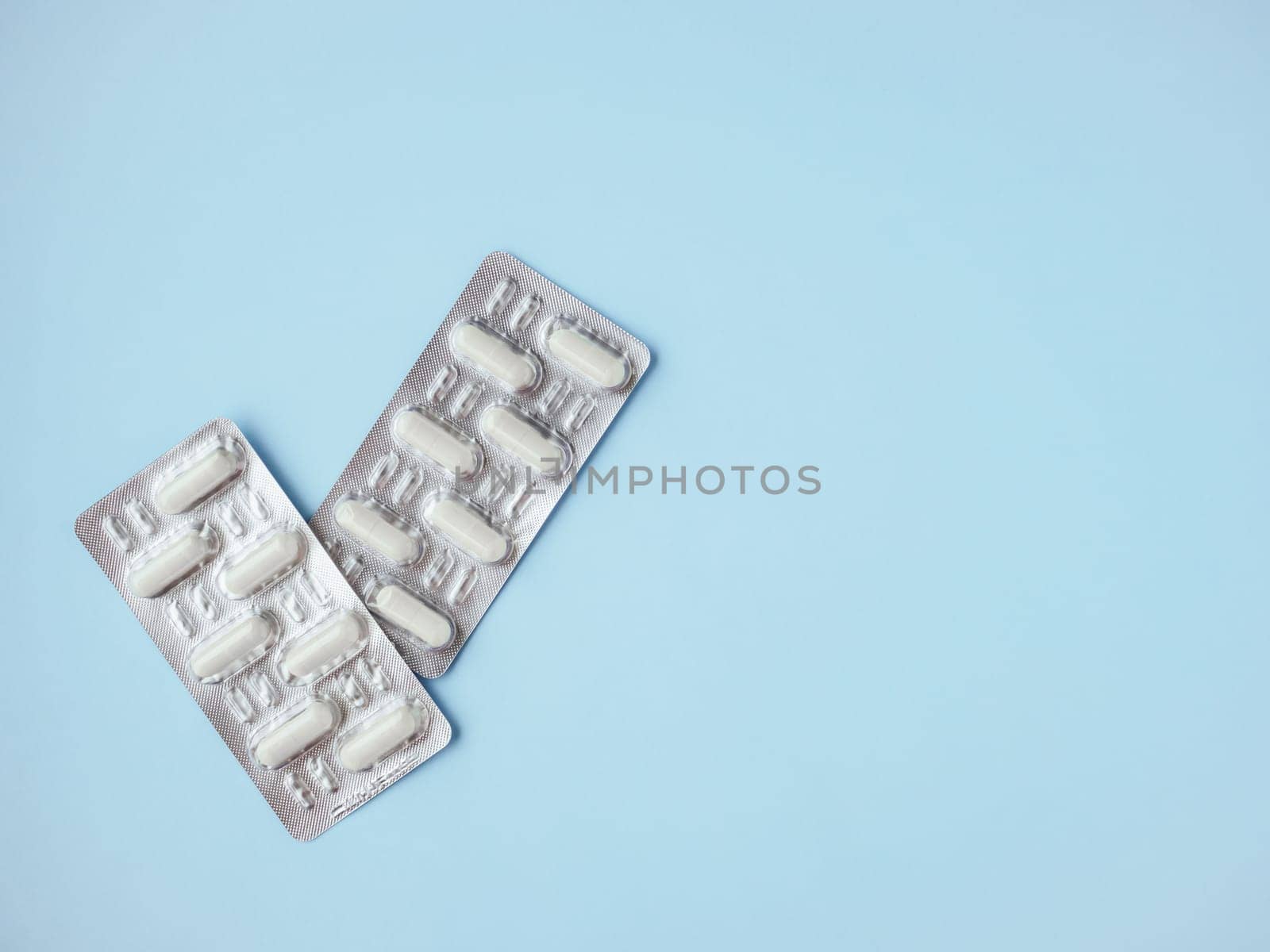 Pharmaceutical medicament, cure in container for health. Medicine pills or capsules on blister pack on blue background with copy space. Drug prescription for treatment medication. Antibiotic