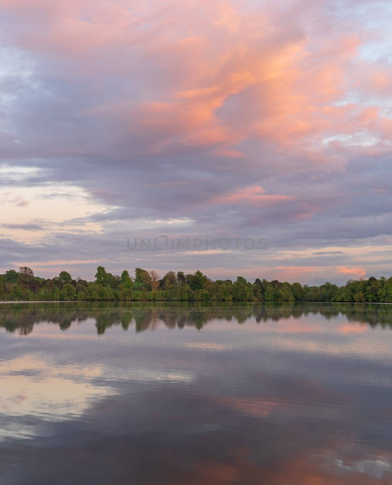 View across the Ellesmere Mere to a clear reflection of distant trees by steheap