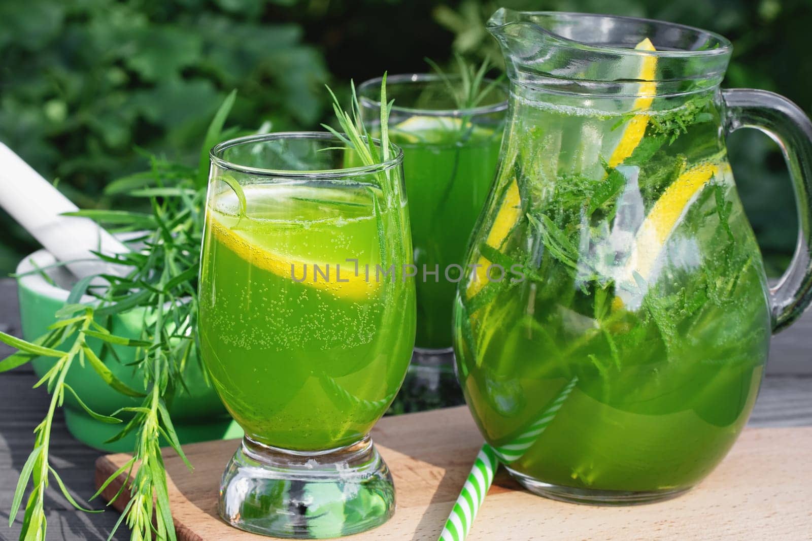 Homemade summer refreshing tarragon lemon drink on patio table.