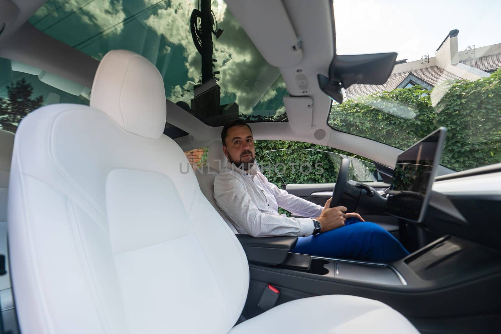 Caucasian bearded man in a suit driving a car