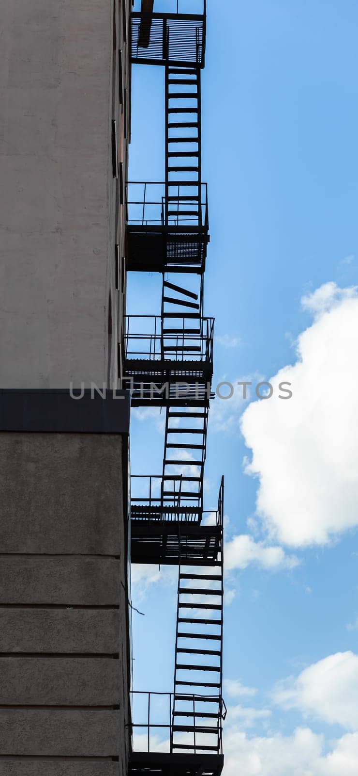 Silhouette of a fire escape on a high-rise building against a blue sky by AnatoliiFoto