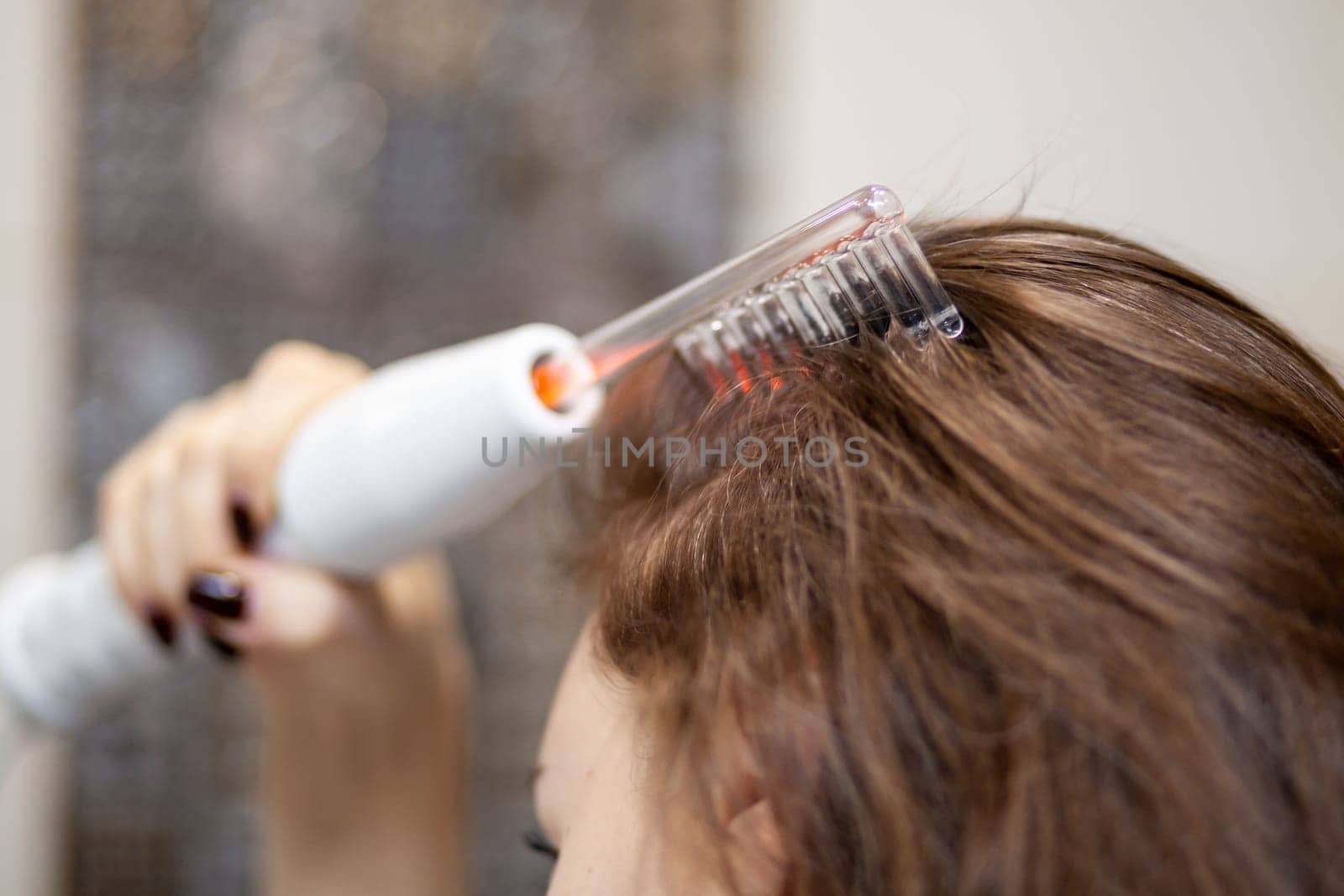 Woman uses darsonval for massage head's skin. by AnatoliiFoto