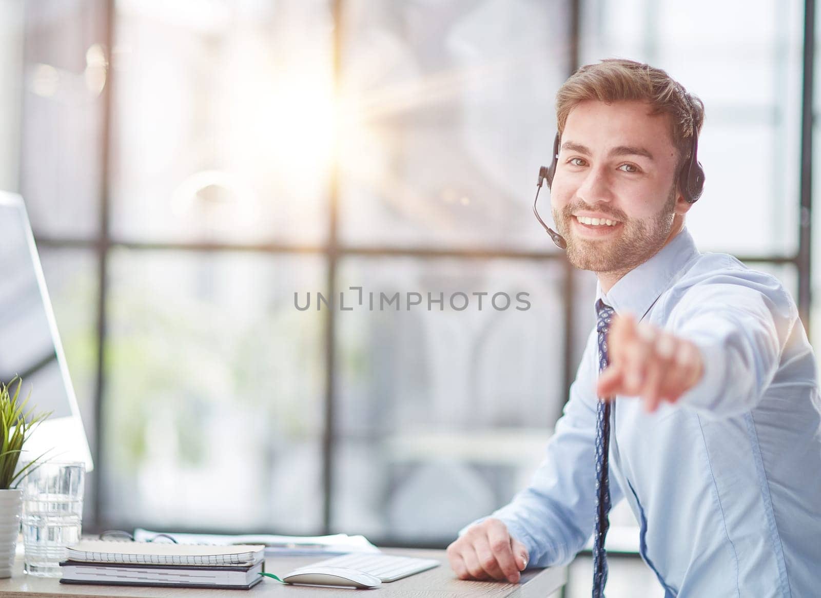Young handsome male customer support phone operator with headset working in his office