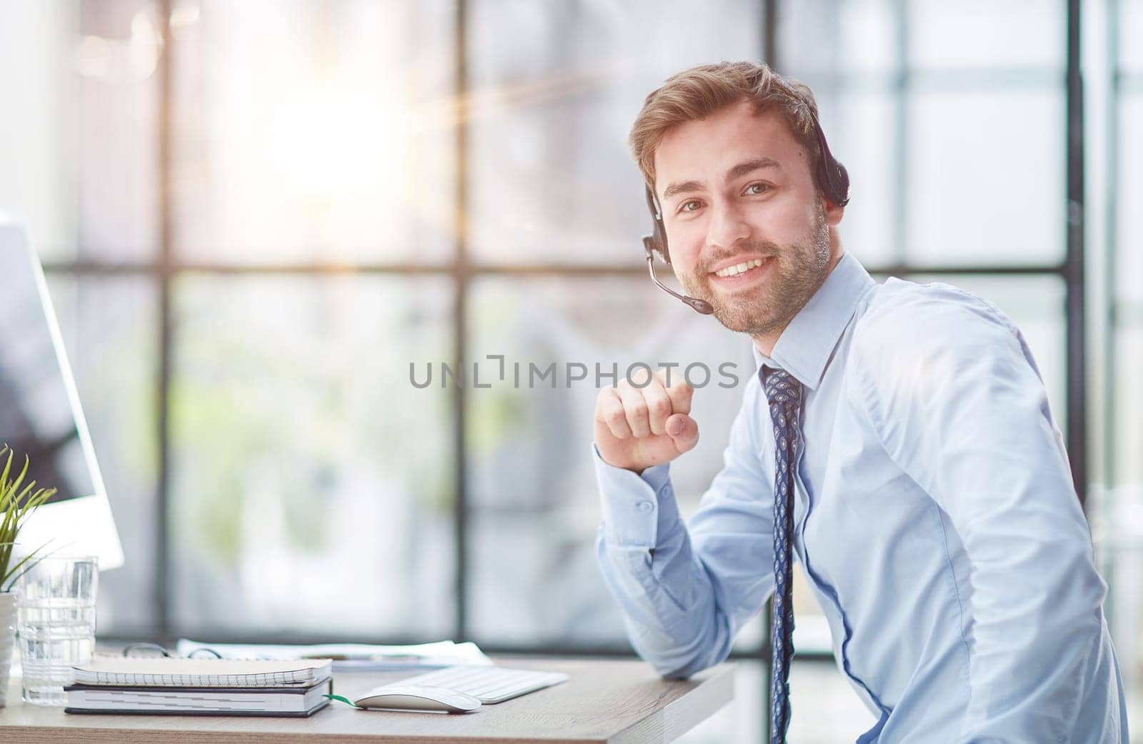 Young handsome male customer support phone operator with headset working in his office