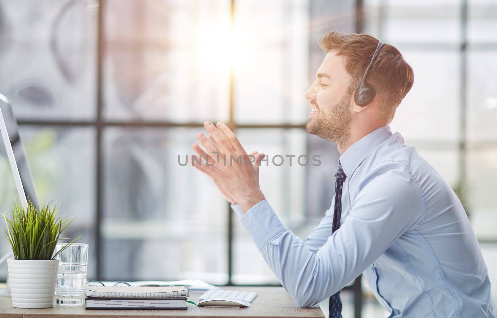 Young handsome male customer support phone operator with headset working in his office