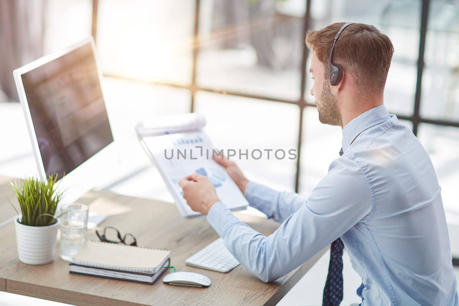 Young handsome male customer support phone operator with headset working in his office