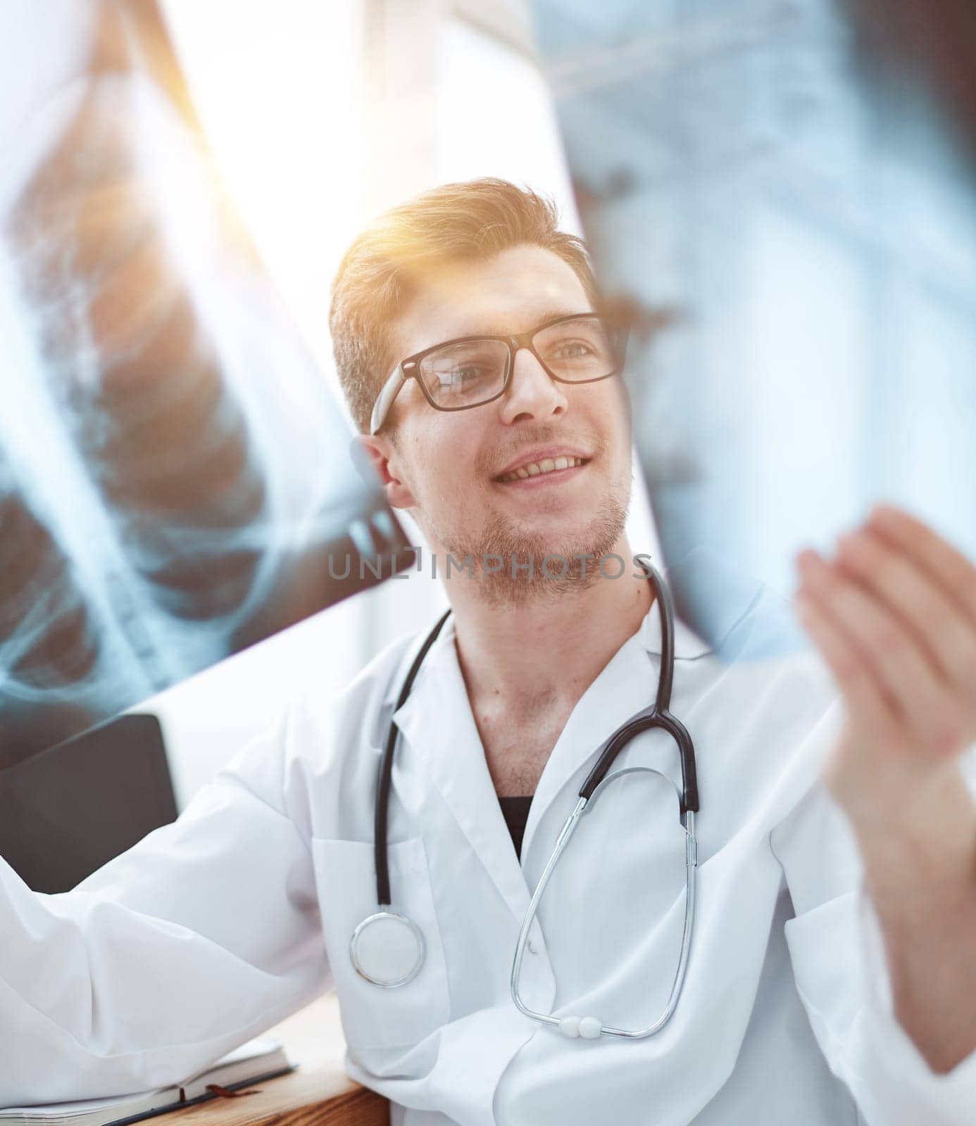 Male doctor in glass radiologist examines x-rays in a medical office.