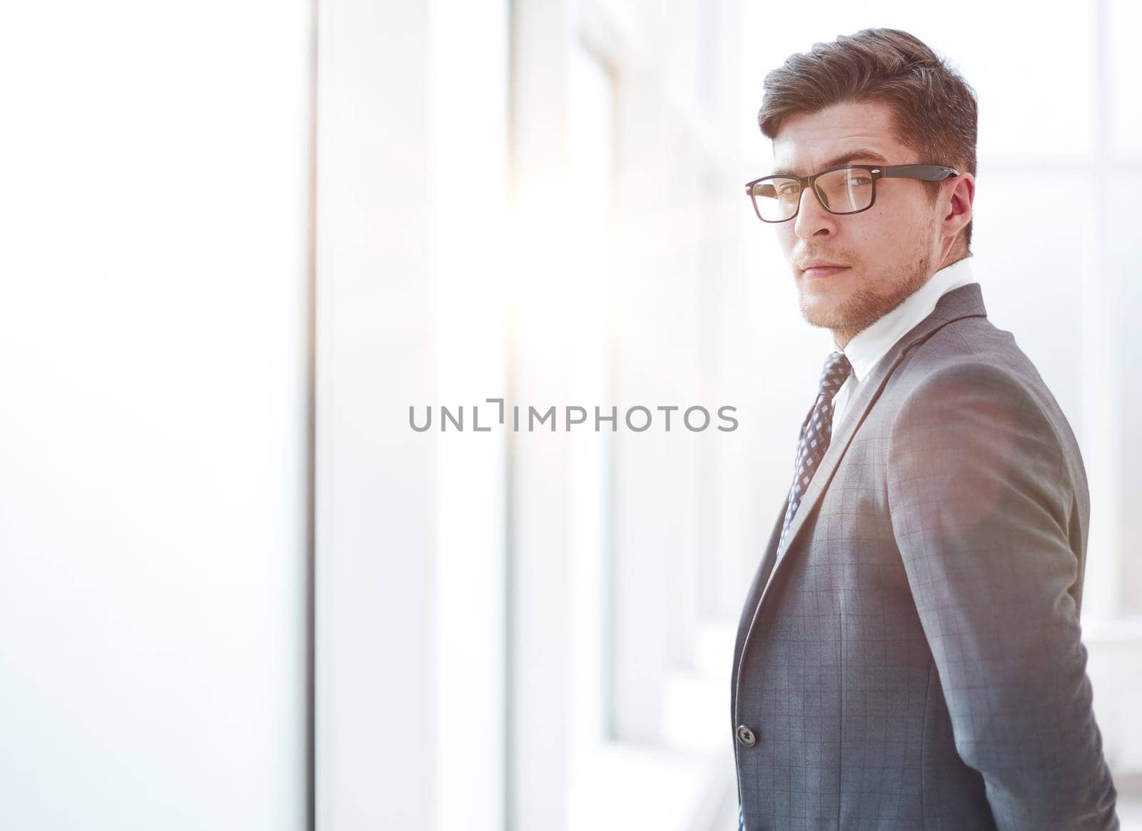 Portrait of a young businessman wearing glasses and standing in office
