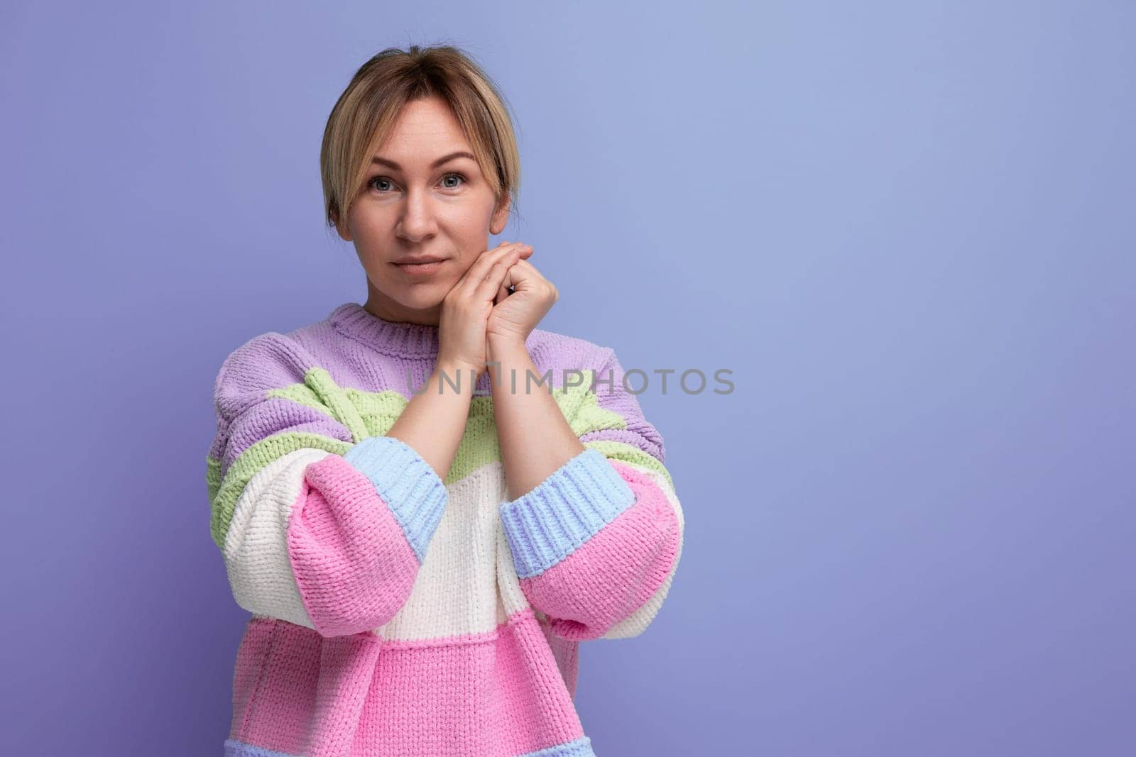 focused blond young woman in casual outfit looking seriously at camera on purple background with copy space by TRMK