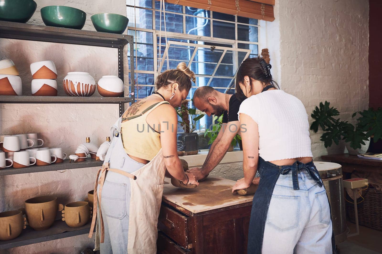 Embrace the beauty of the mess. a group of young people kneading clay in a pottery studio