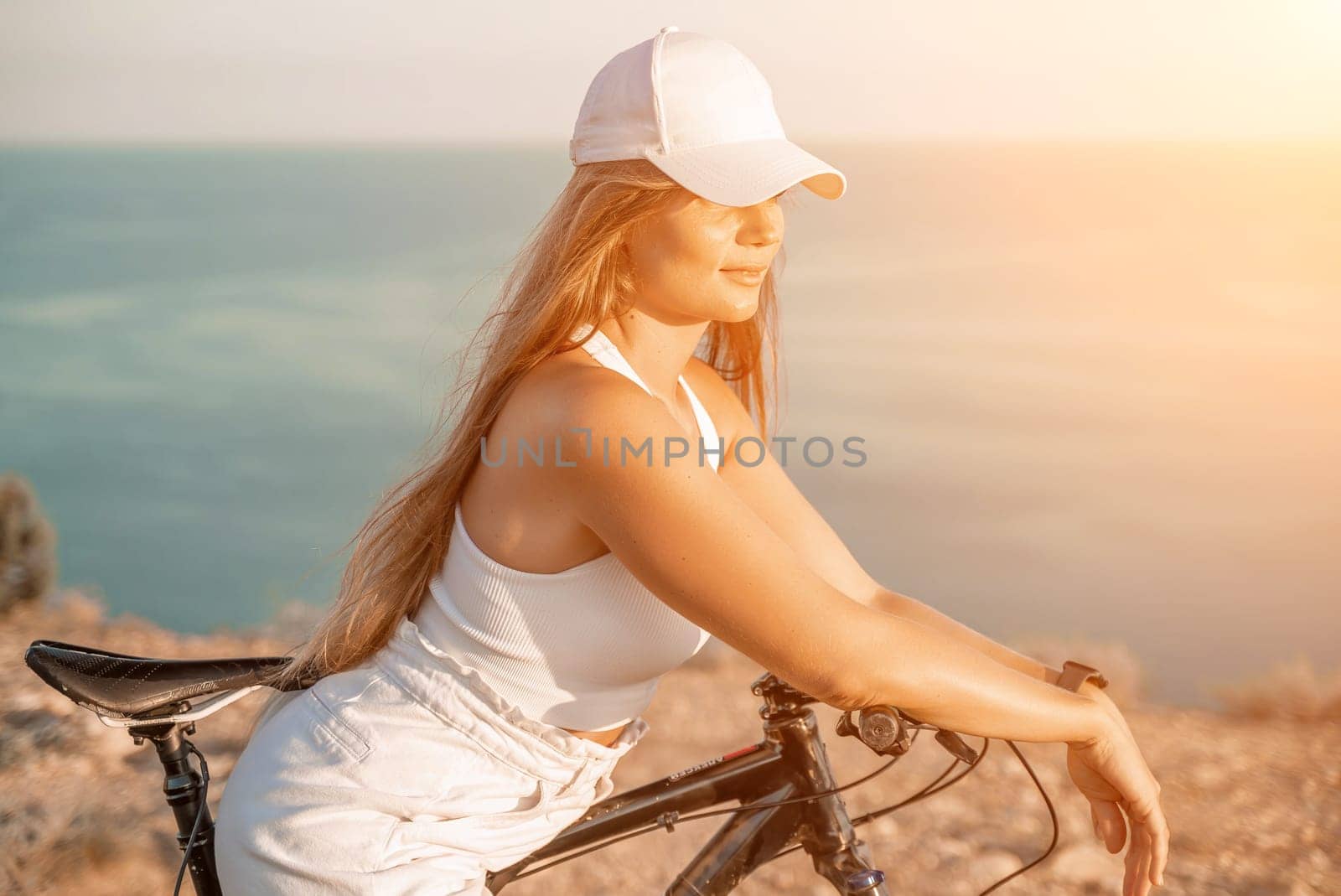 Woman travel bike sea. Happy woman cyclist sitting on her bike, enjoying the beautiful mountain and sea landscape, signifying the idea of an adventurous bike ride