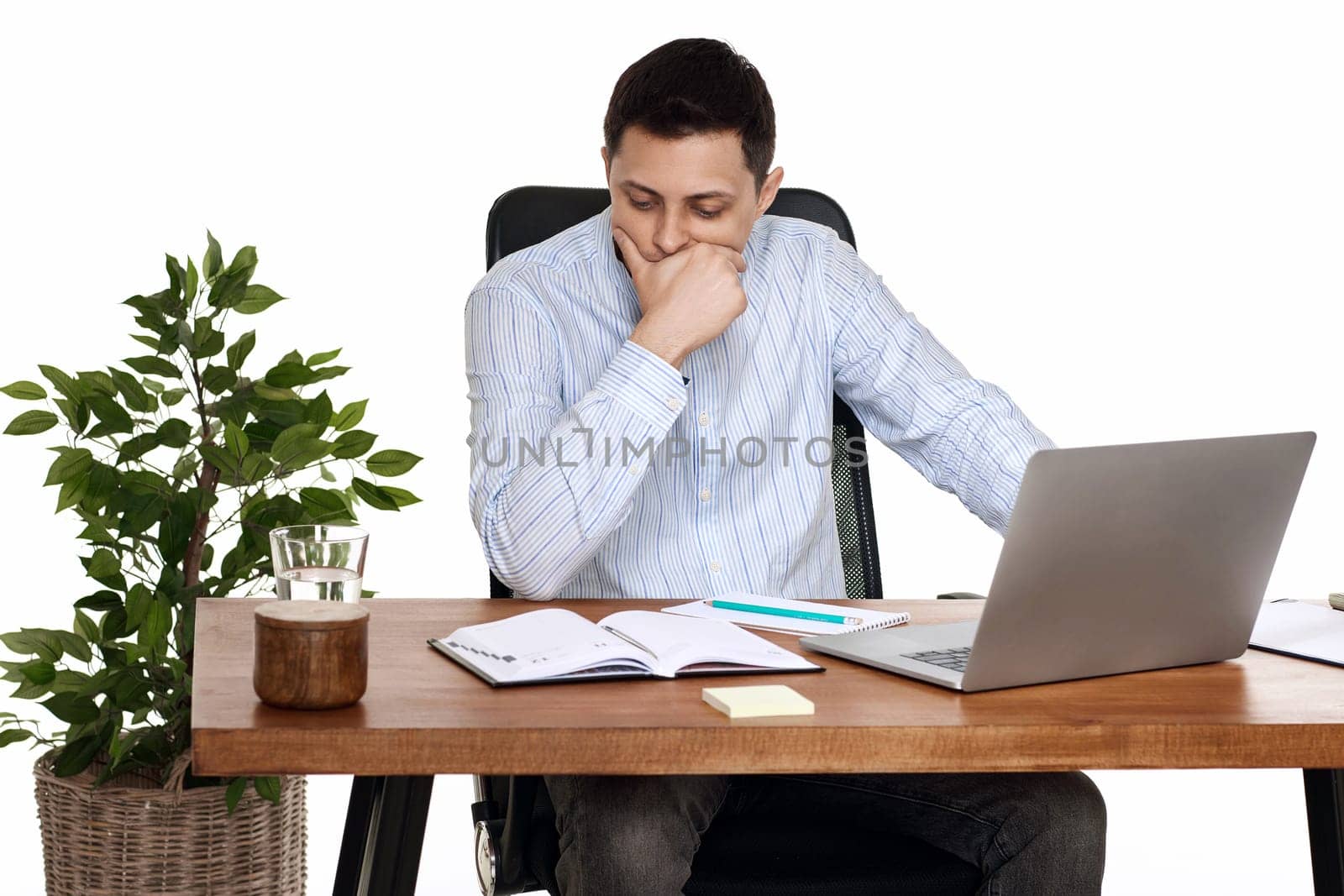 sad businessman using laptop, sitting on chair at desk, having problems thinking about troubles in office