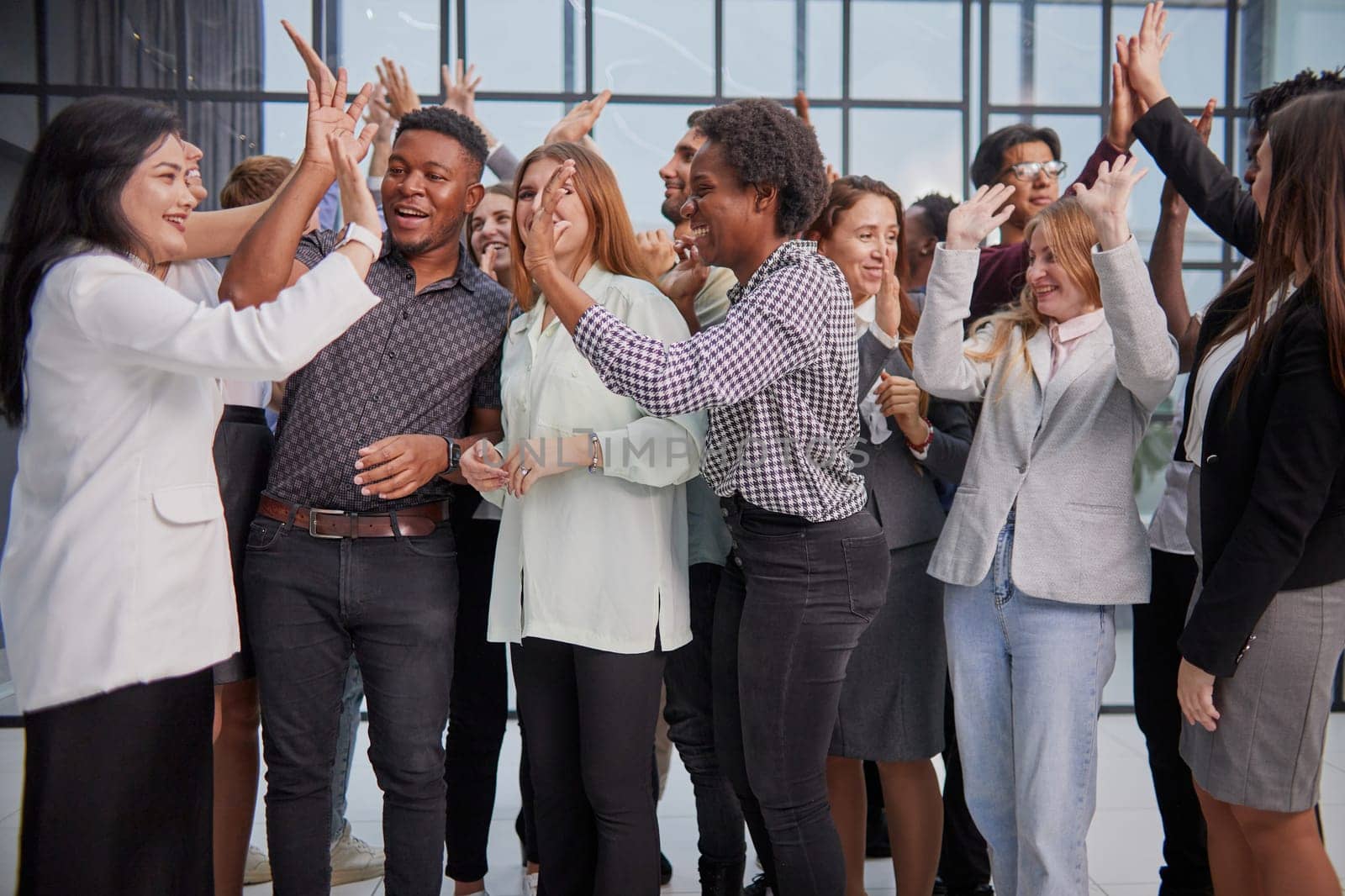Excited multinational employees celebrating team victory giving high five