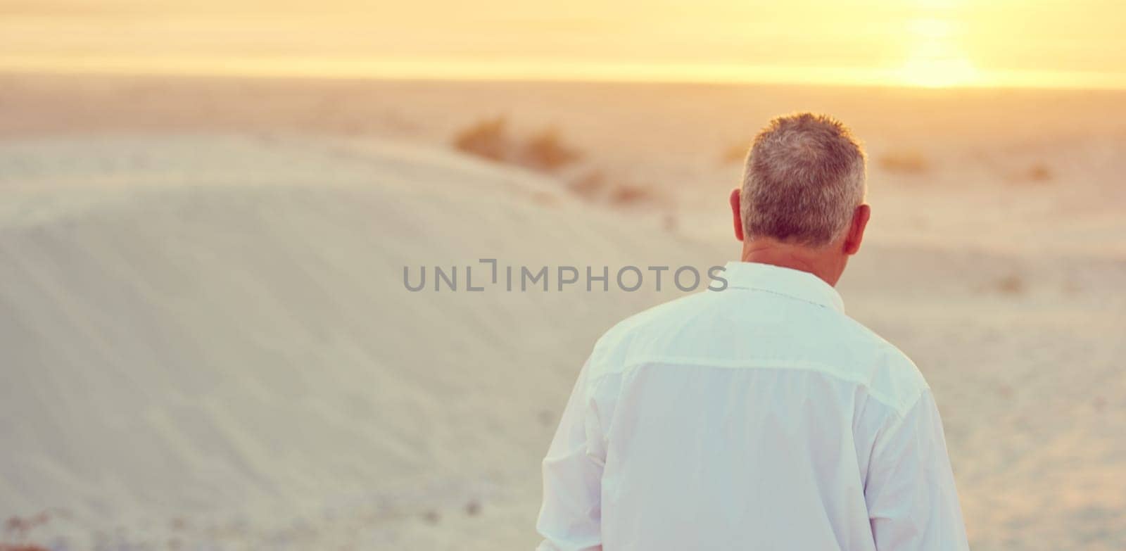 Find your own paradise. Rearview shot of mature man walking on the beach at sunset