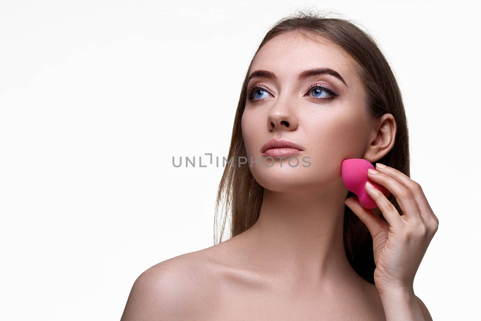attractive young woman using pink cosmetic sponges isolated on white background. copy space
