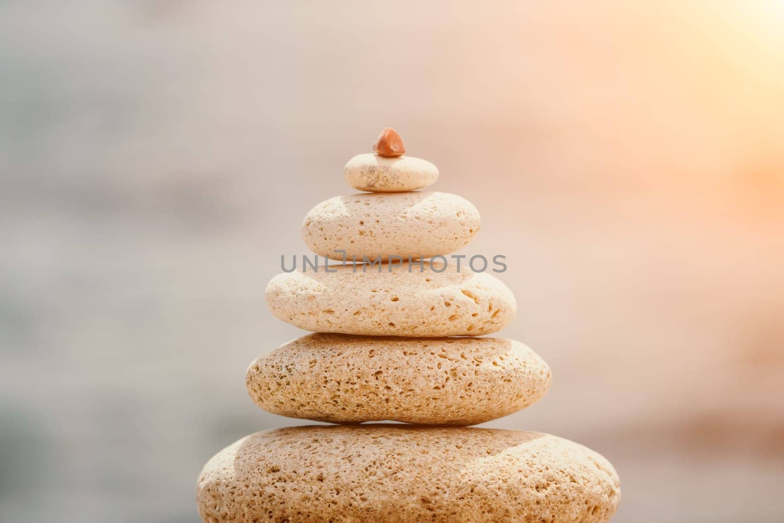 Pyramid stones on the seashore with warm sunset on the sea background. Happy holidays. Pebble beach, calm sea, travel destination. Concept of happy vacation on the sea, meditation, spa, calmness.