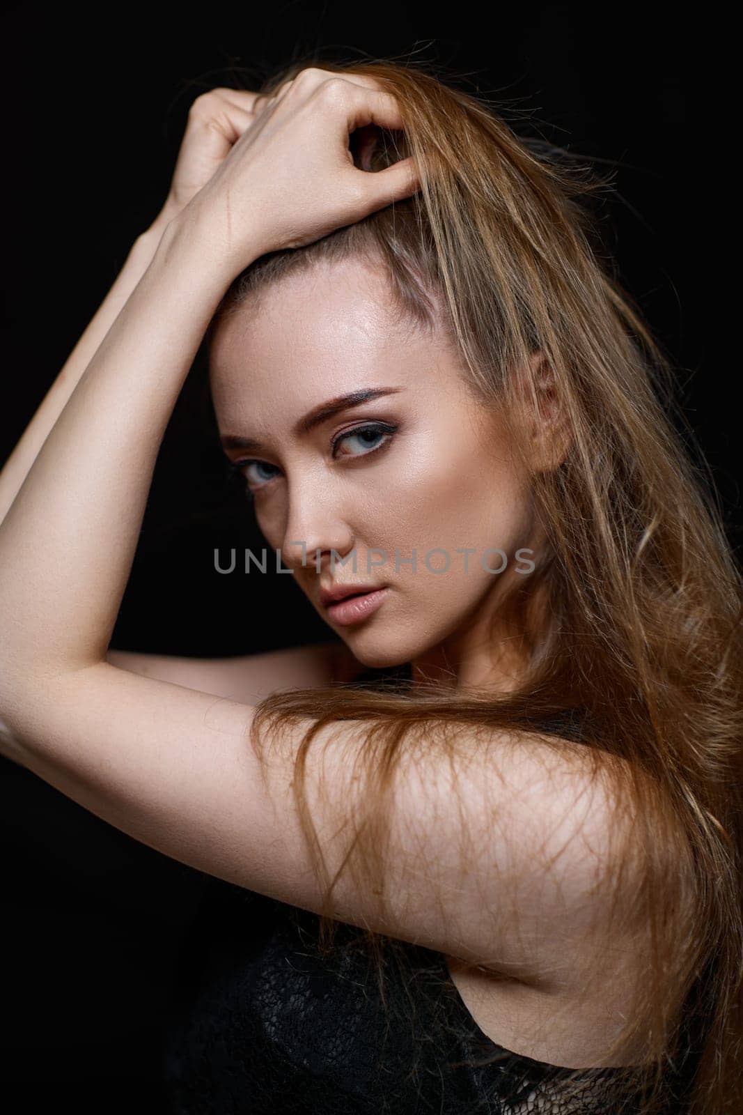 gorgeous brunette woman with long hair in black dress on black background