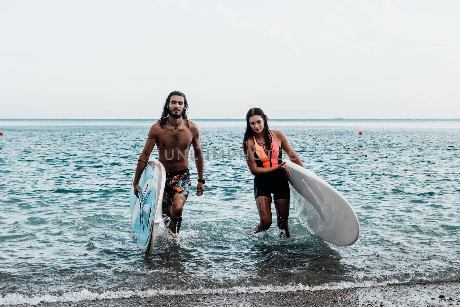 Sea woman and man on sup. Silhouette of happy young woman and man, surfing on SUP board, confident paddling through water surface. Idyllic sunset. Active lifestyle at sea or river